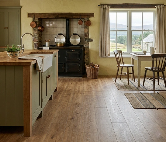 Durable and authentic wood-effect Luxury Vinyl Tile (LVT) flooring installation in a traditional Highland farmhouse kitchen in Inverness, featuring rustic green cabinetry and an AGA-style range