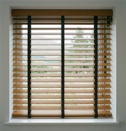 Close-up view of newly installed, real wooden Venetian blinds in natural oak, featuring decorative black fabric tapes, in a contemporary Inverness home. The high-quality blinds, fitted perfectly to a white uPVC window frame with a loch view, showcase professional installation and modern style