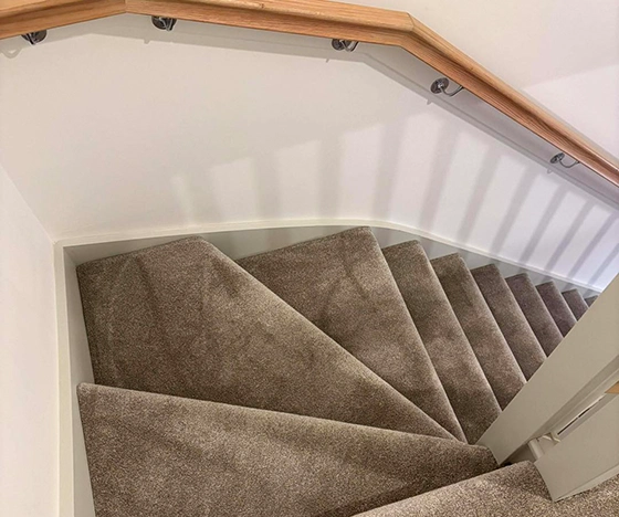 Expertly fitted taupe carpet on winder stairs in an Inverness home by Ness Blinds & Floors, showcasing high-quality craftsmanship and a premium finish
